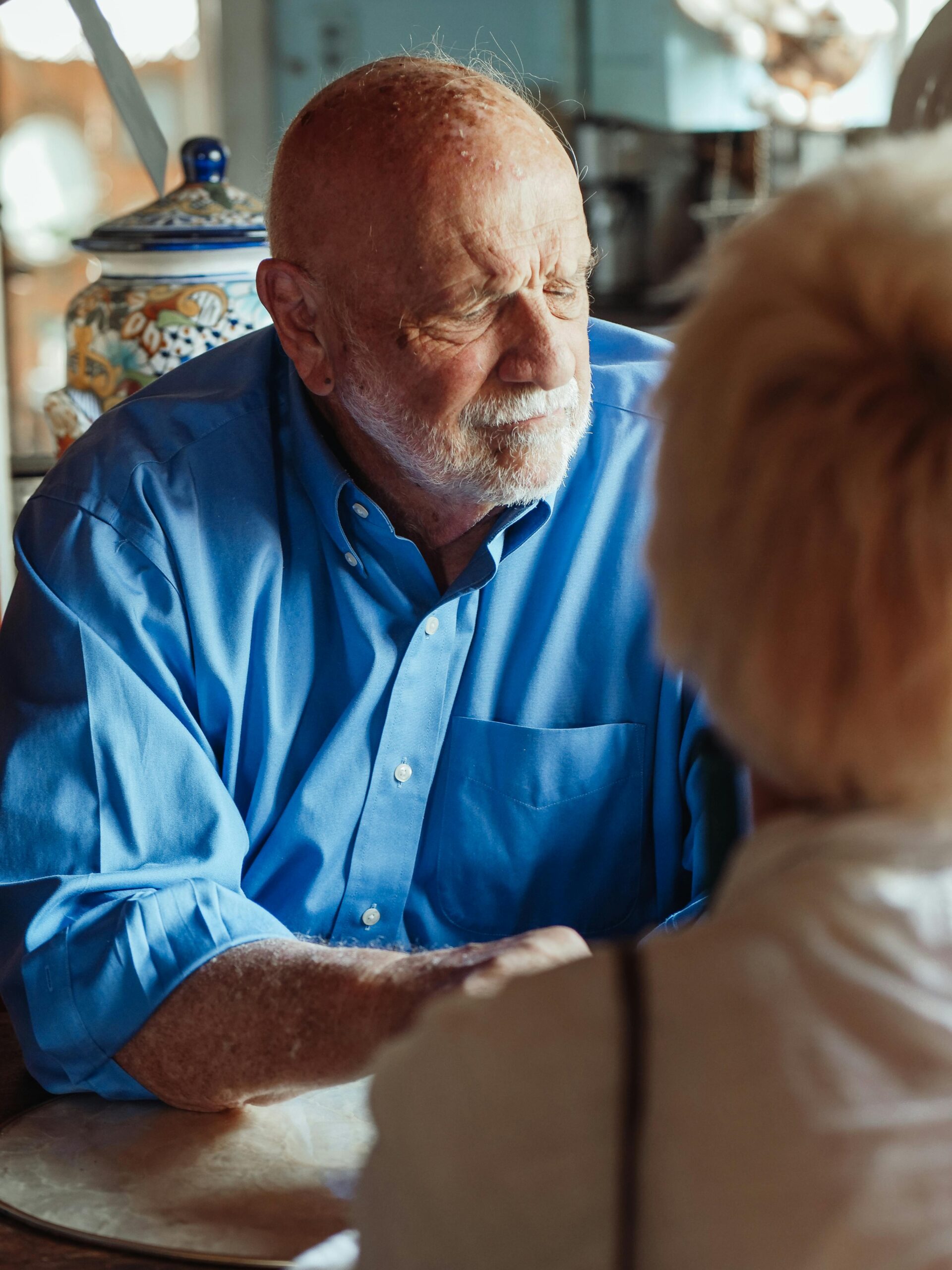 Elderly man in blue shirt in a reflective moment indoors, hinting at nostalgia.